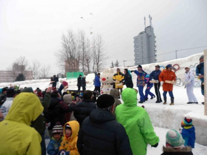 雪の祭典で、檀上から、観客に向かって餅を撒く人々の画像