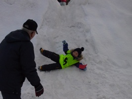 幼稚園で開催された雪中あそびの会場で、雪山から滑って遊ぶ子供の画像