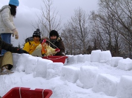 稲積公園冬祭りで、雪で作った滑り台をそりで滑って遊ぶ様子の、子供の画像