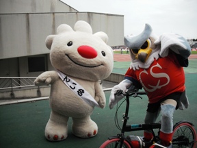 厚別公園陸上競技場で、自転車に乗ったコンサドーレ札幌のマスコットキャラクター、ドーレ君と記念撮影をする、ていぬの画像