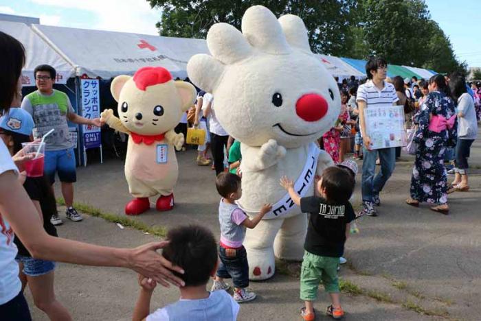 ていね夏あかりの会場で、北海道科学大学のマスコットキャラクターと一緒に、子供たちと触れ合う、ていぬの画像