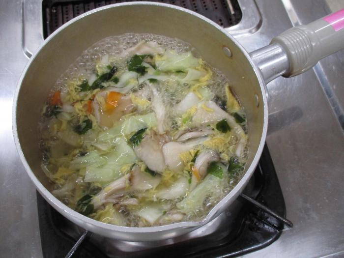 鍋に粉末スープを溶かし、パックごはんと餃子を加える様子