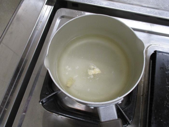 鍋で鶏がらスープの素、しょうがチューブ、水を煮立たせる様子