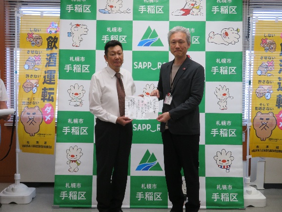 里手稲区長から豊嶋手稲料飲店旅館協会会長に「ていぬの書」を交付している様子