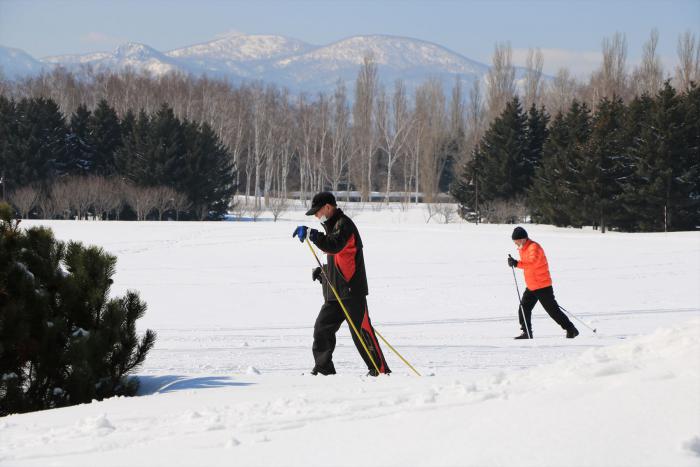 写真：手稲山をバックに歩くスキー