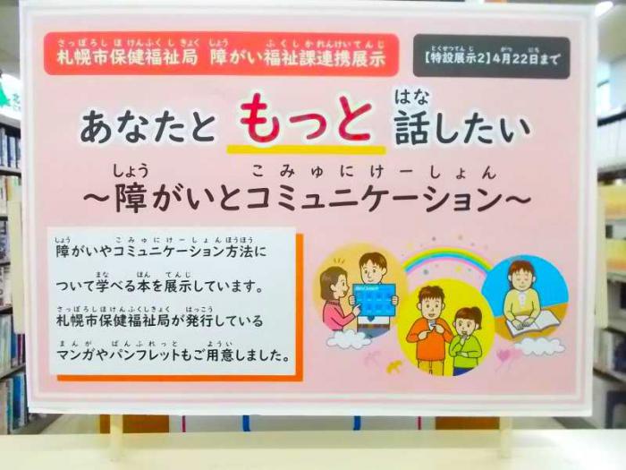 展示の看板の写真。手話や点字などでコミュニケーションをとる人のイラストを添えています。