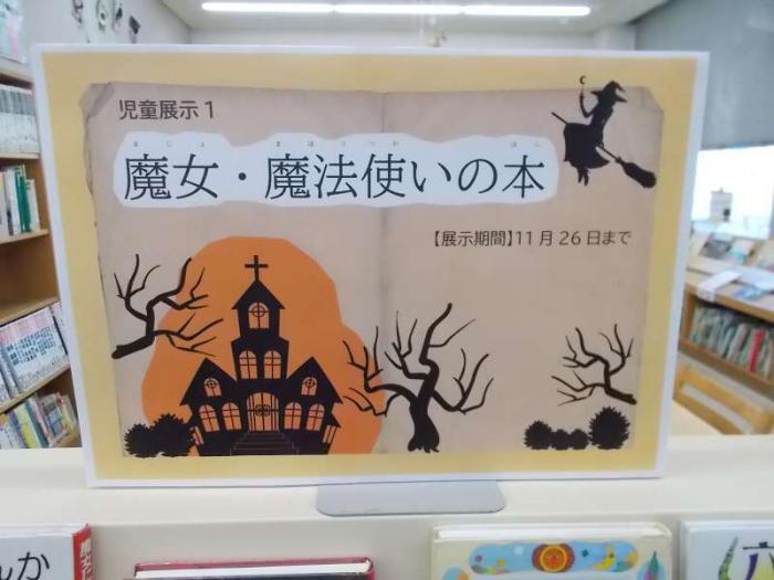 展示の看板写真です。切り絵風の魔女やお屋敷のイラストを添えています。