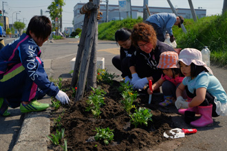 子どもたちといっしょに花を植えるノルディーア北海道の選手とスタッフ