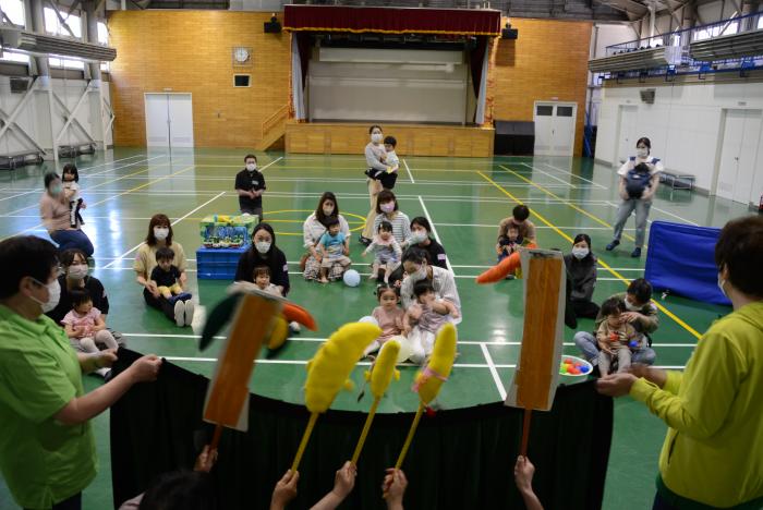 会場の床に座り子どもを膝の上に乗せて人形劇を鑑賞する様子