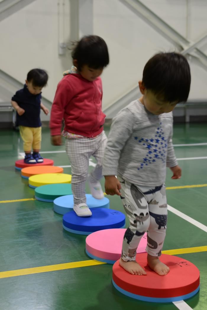 丸いプレートに並んで乗って遊ぶ3人の子ども