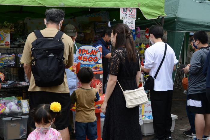 縁日コーナーの前に立って悩んでいる親子